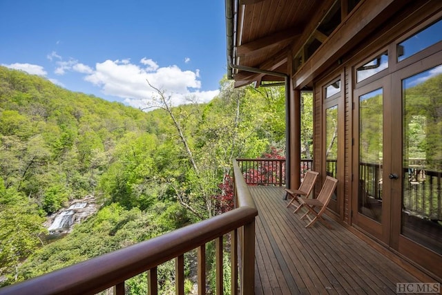 wooden terrace featuring french doors and a forest view