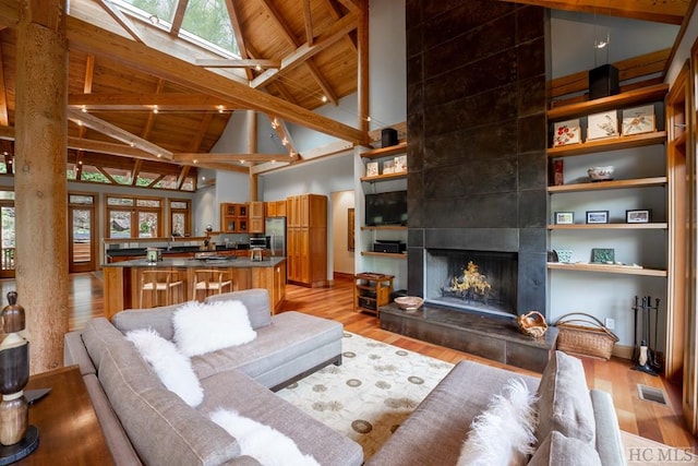 living area featuring wooden ceiling, a skylight, light wood finished floors, and beam ceiling