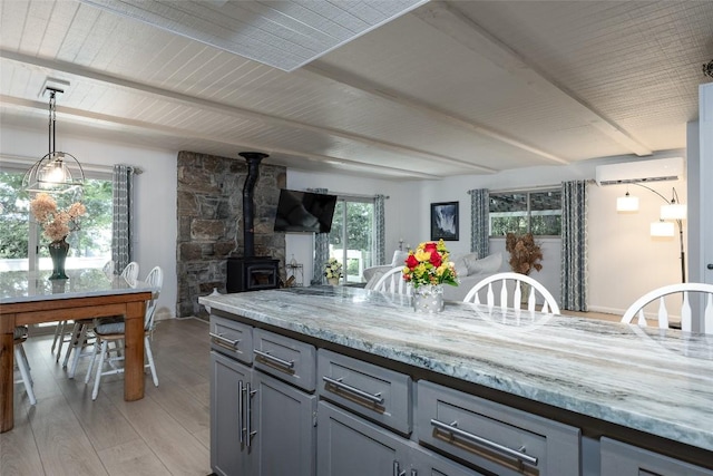 142 Wheatstone Dr, Glenville, NC 28736 - kitchen with open floor plan, a wall mounted air conditioner, light wood-style flooring, gray cabinetry, and a wood stove