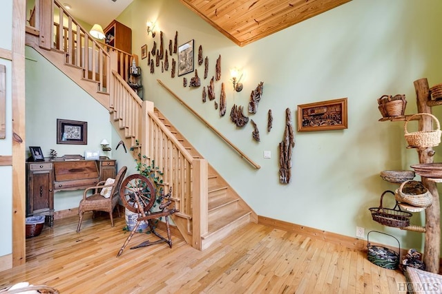 stairs with wood ceiling, a high ceiling, and wood-type flooring