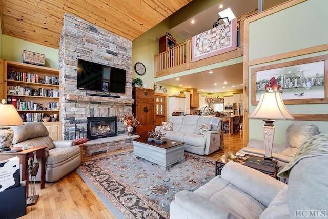 living room featuring a fireplace, light wood-type flooring, a high ceiling, and wooden ceiling