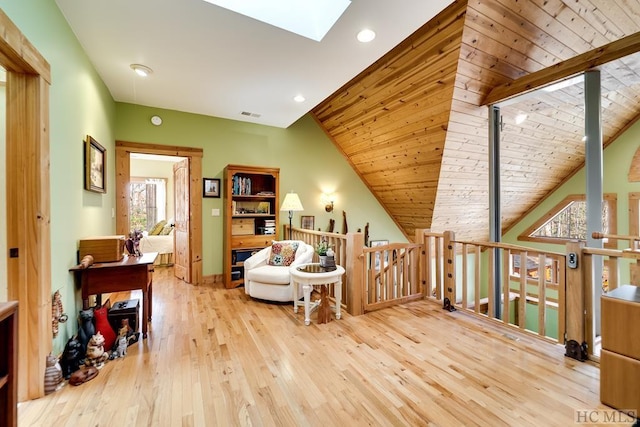 living area with light hardwood / wood-style floors, wooden ceiling, and lofted ceiling with skylight