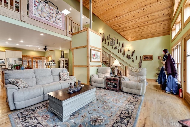 living room with ceiling fan, light hardwood / wood-style flooring, a towering ceiling, and wooden ceiling