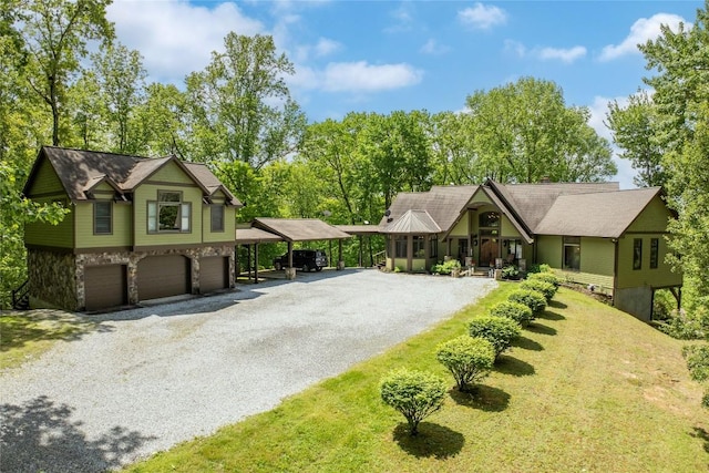view of front of home featuring driveway, stone siding, a garage, and a front yard