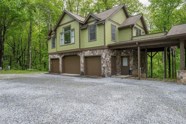 view of front of home with an attached garage, driveway, stone siding, and a shingled roof