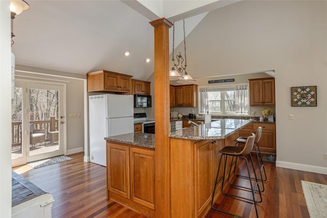 kitchen with electric stove, black microwave, freestanding refrigerator, a kitchen island, and brown cabinetry