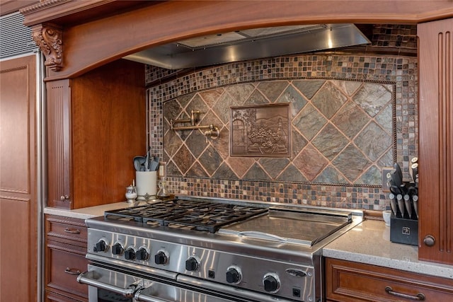 kitchen with range with two ovens, decorative backsplash, brown cabinets, and light stone countertops