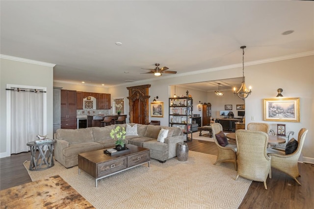 living area with wood finished floors, ornamental molding, ceiling fan, a chandelier, and baseboards