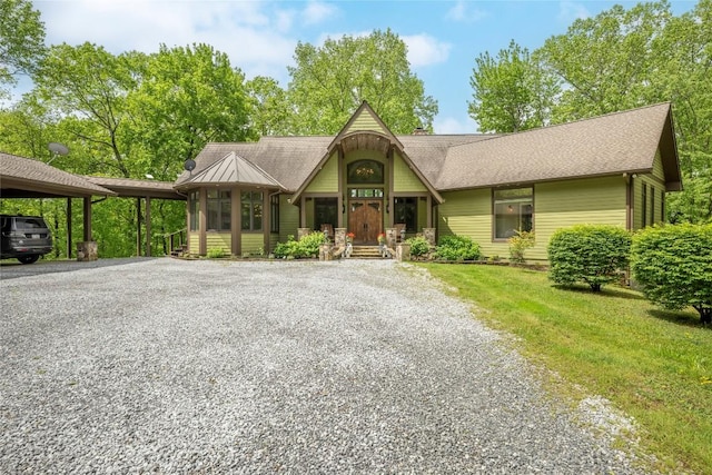 view of front of property featuring gravel driveway, a carport, a front yard, a porch, and a shingled roof