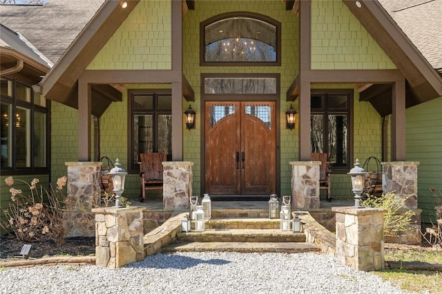 entrance to property featuring a porch, a shingled roof, and french doors