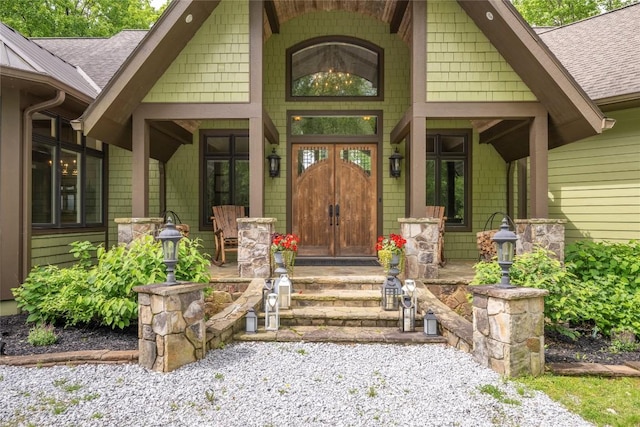 entrance to property featuring covered porch and roof with shingles