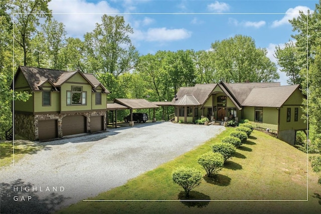 view of front of house with driveway, an attached garage, a carport, stone siding, and a front yard