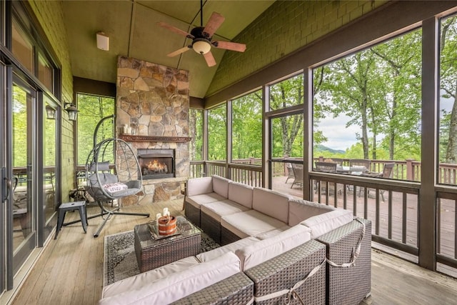 sunroom with a ceiling fan, an outdoor living space with a fireplace, and lofted ceiling