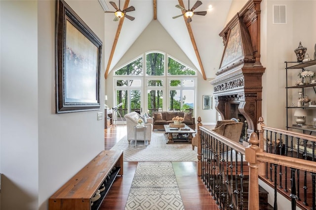 living area featuring ceiling fan, dark wood-type flooring, high vaulted ceiling, a fireplace, and beam ceiling