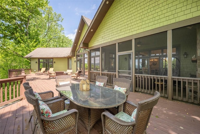 wooden terrace with outdoor dining space and a sunroom