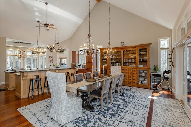 dining area featuring a chandelier, high vaulted ceiling, dark wood finished floors, and plenty of natural light