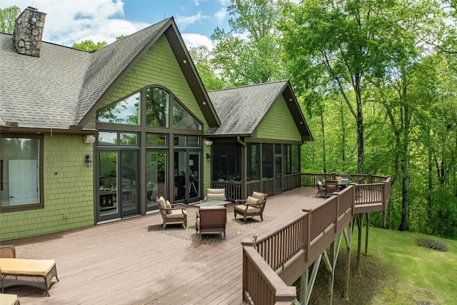 deck with a sunroom and an outdoor living space with a fire pit