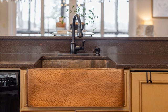 kitchen featuring dark countertops, a sink, and dishwashing machine