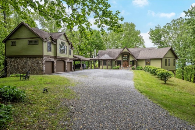 view of front of property with gravel driveway, stone siding, an attached garage, and a front yard