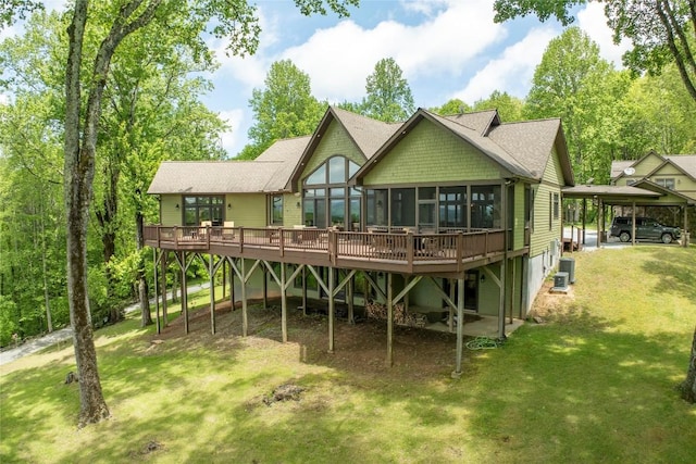 rear view of property with a wooden deck, a sunroom, a lawn, and a shingled roof