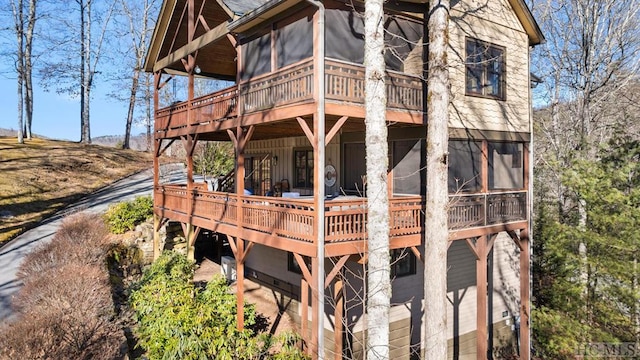 back of property featuring a sunroom and a wooden deck