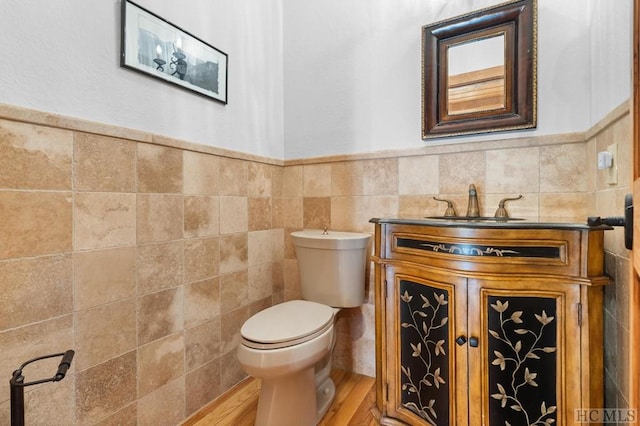 bathroom with tile walls, wood-type flooring, vanity, and toilet