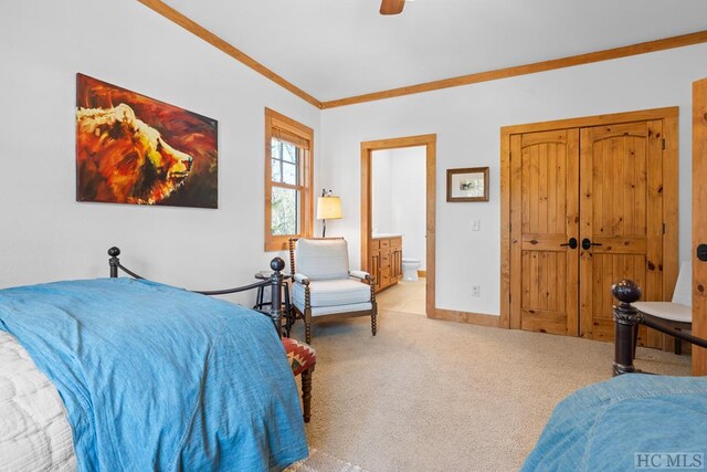 carpeted bedroom with ensuite bathroom, ceiling fan, and ornamental molding