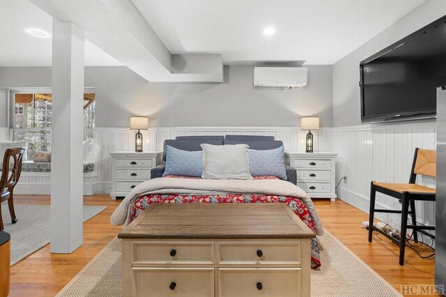 bedroom with light wood-type flooring and a wall mounted AC