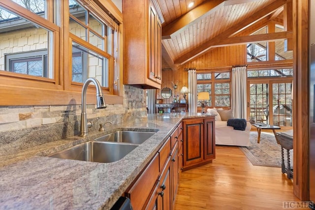 kitchen featuring light wood-type flooring, wood ceiling, beam ceiling, light stone countertops, and sink