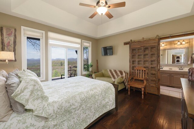 129 Skyline Park Dr, Franklin, NC 28734 - bedroom with dark wood-type flooring, a barn door, ensuite bath, a sink, and a ceiling fan