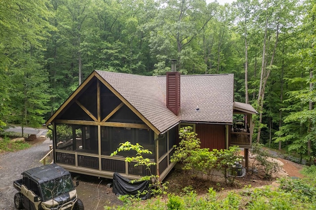 45 Boulder Creek Ln, Tuckasegee, NC 28783 - view of front of property featuring a wooded view, a chimney, a sunroom, and roof with shingles