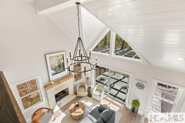 living area featuring wood finished floors, beamed ceiling, a chandelier, a fireplace, and high vaulted ceiling