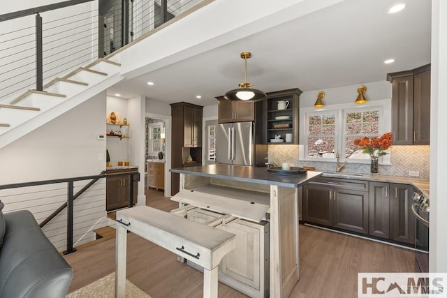 kitchen featuring appliances with stainless steel finishes, a sink, open shelves, light wood-style flooring, and recessed lighting