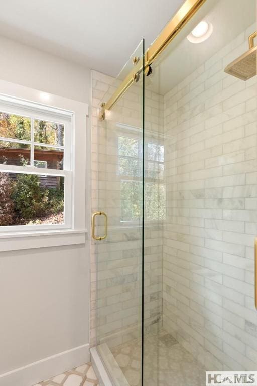 bathroom featuring plenty of natural light, a stall shower, and baseboards