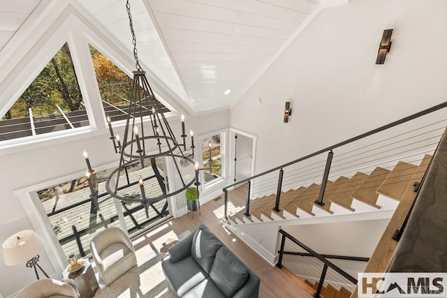 staircase with wood finished floors, lofted ceiling, a chandelier, and baseboards