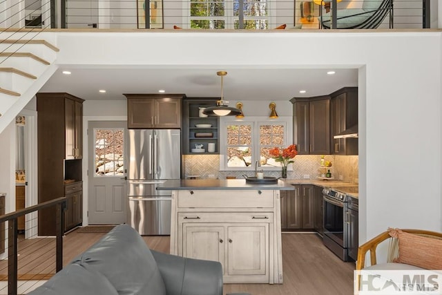kitchen featuring stainless steel appliances, plenty of natural light, light wood-style floors, recessed lighting, and a high ceiling