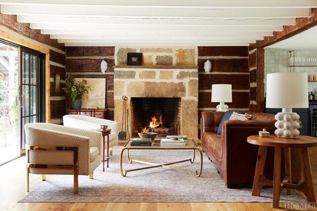 sitting room featuring hardwood / wood-style flooring, a stone fireplace, and beam ceiling