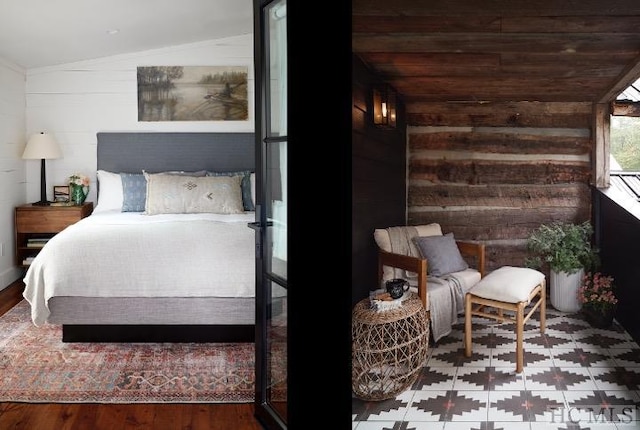 bedroom with vaulted ceiling, hardwood / wood-style floors, and wood walls