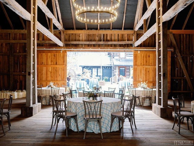 dining space featuring wooden walls, an inviting chandelier, and wood-type flooring