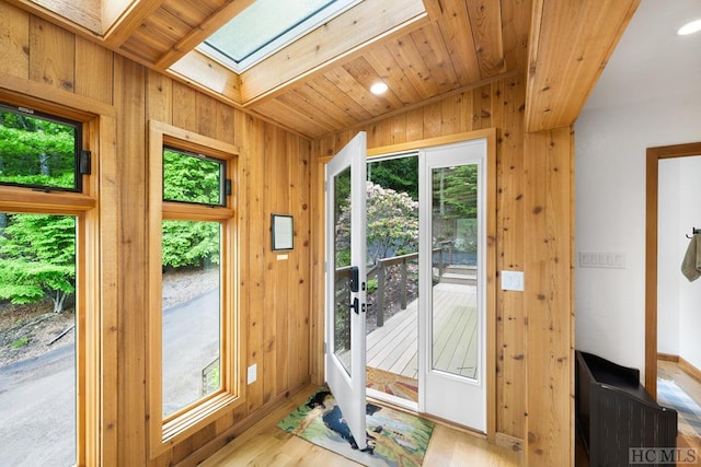 doorway to outside featuring wood ceiling, plenty of natural light, a skylight, and light wood-type flooring