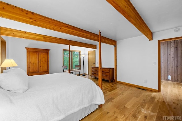 bedroom with beamed ceiling and light hardwood / wood-style floors