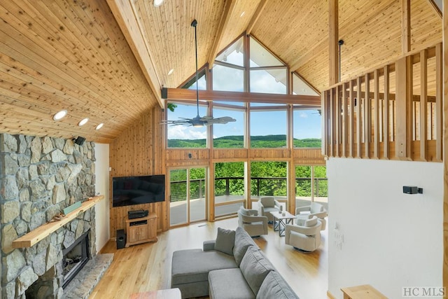 living room with a stone fireplace, light hardwood / wood-style flooring, high vaulted ceiling, and beamed ceiling