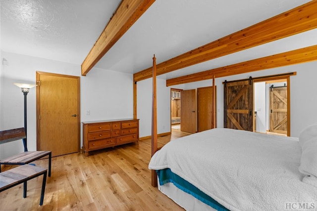 bedroom with beamed ceiling, a barn door, a closet, and light wood-type flooring