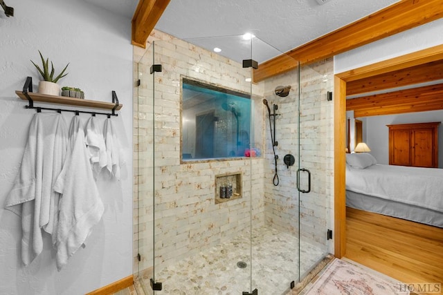 bathroom with a shower with door and beam ceiling