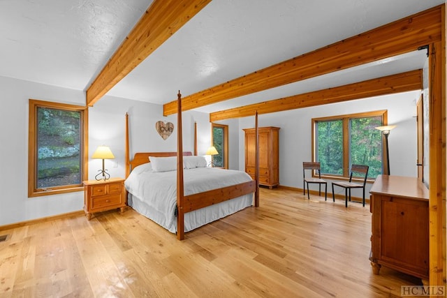 bedroom featuring beamed ceiling and light hardwood / wood-style floors