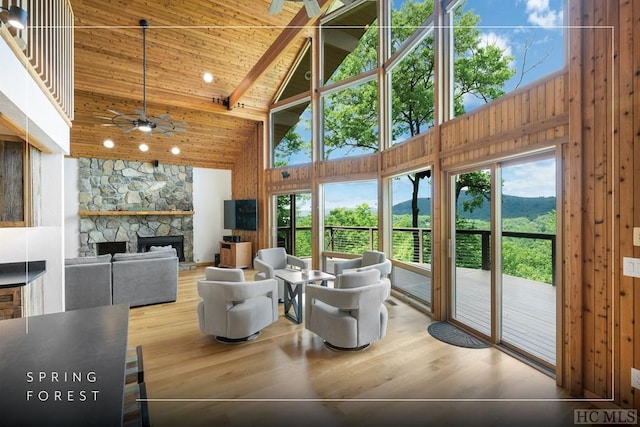 sunroom featuring lofted ceiling with beams, ceiling fan, wooden ceiling, and a fireplace