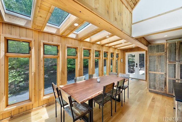 sunroom with beam ceiling, a skylight, and french doors