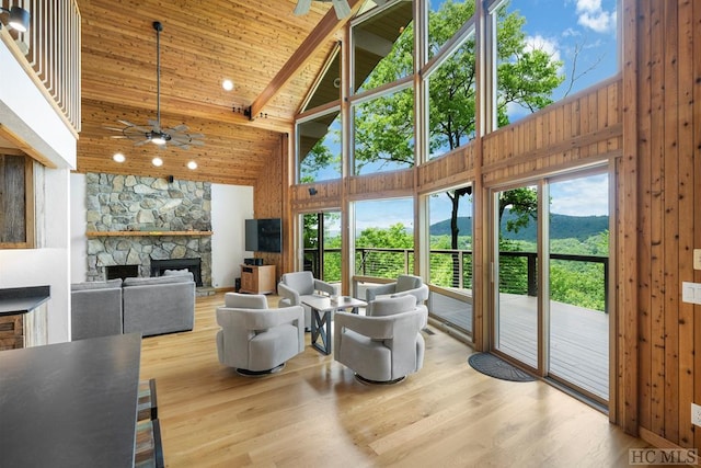 sunroom with ceiling fan, vaulted ceiling with beams, wooden ceiling, and a fireplace