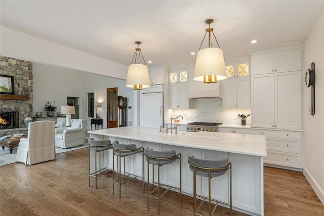 510 Boiling Springs Rd, Sapphire, NC 28774 - kitchen featuring white cabinets, dark wood-style flooring, an island with sink, a breakfast bar area, and a stone fireplace