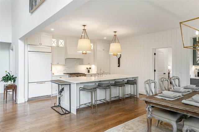 510 Boiling Springs Rd, Sapphire, NC 28774 - kitchen with paneled refrigerator, custom exhaust hood, wood finished floors, white cabinets, and light countertops